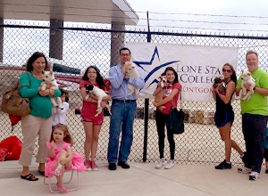 Students and professor Mike Devoley saying goodbye to puppies in front of an airplane.