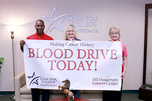 blood drive banner held by Kathy Johanson, Dr. Austin Lane, and Sheila Davenport