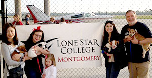airplane in background students and instructor holding puppies