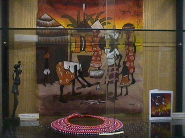 batik cloth depicting a typical village scene; a wood carving; a ceremonial neckpiece; stylized art cards