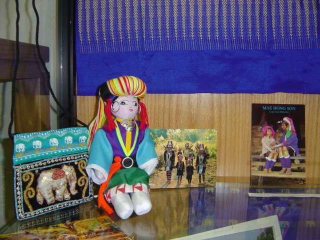 in addition to the silk-cloth backdrop and the silk purse, a doll and photos of the hill people of Thailand