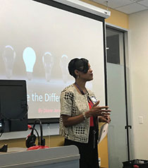 Photo of a teacher in a classroom in front of a projector screen