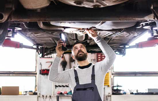 Man inspecting the undercarriage of a car
