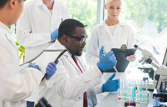 Scientists observing a man pipetting something into test tubes