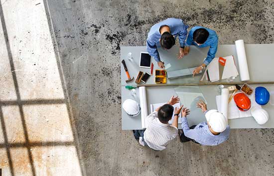 Construction workers work on blueprints around a table