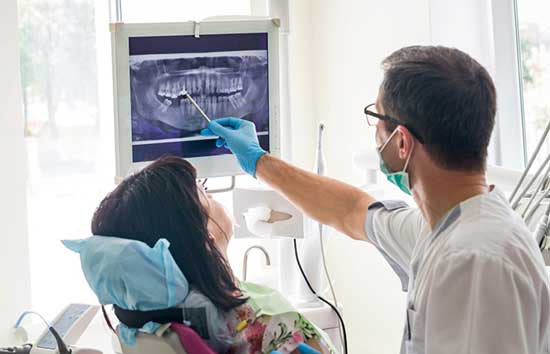 Dentist inspecting a woman's x-ray of her mouse