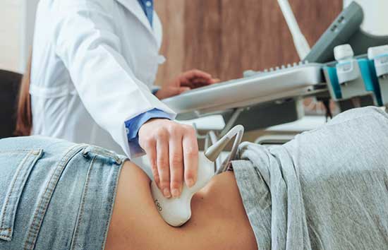 Doctor with a sonography device checking a women's hip