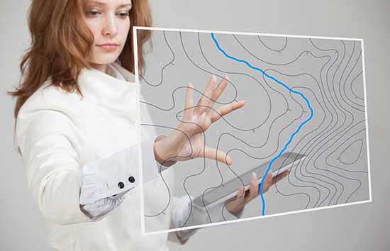 A woman interacting with a holograph of a geographic map