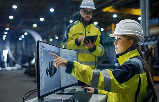 A woman in a hard hat pointing at her monitor