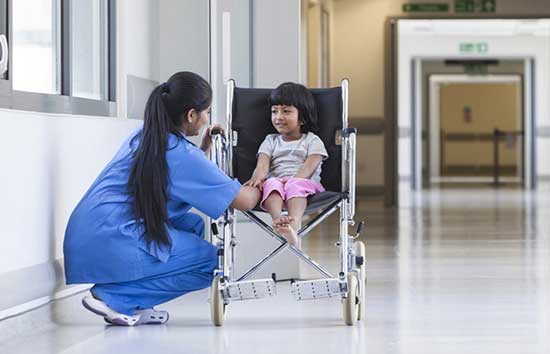 A nurse talking to a child in a wheelchair