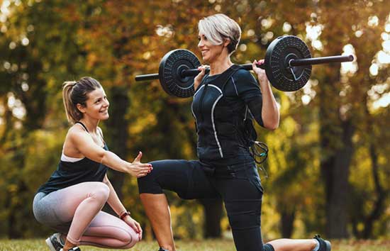 Two women exercising with a barbell