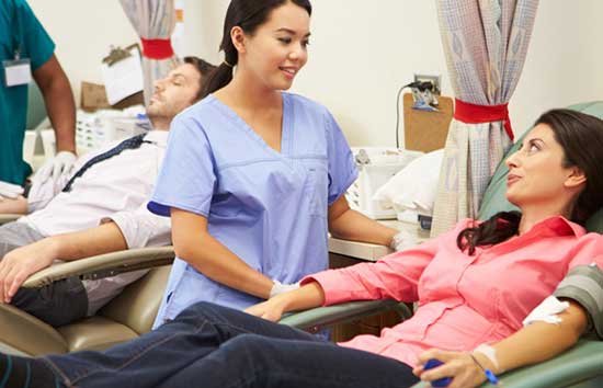 A nurse talking to a woman getting her blood drawn