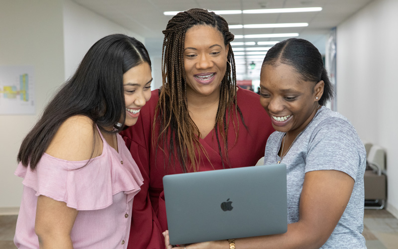 Smiling students looking at a computer 