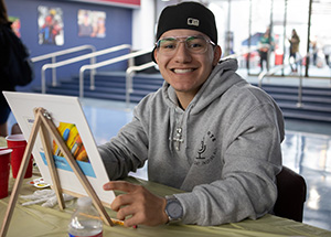 Male student smiling and painting