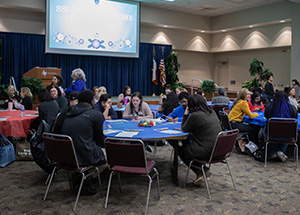 Students having group discussions at round tables at welcome event 