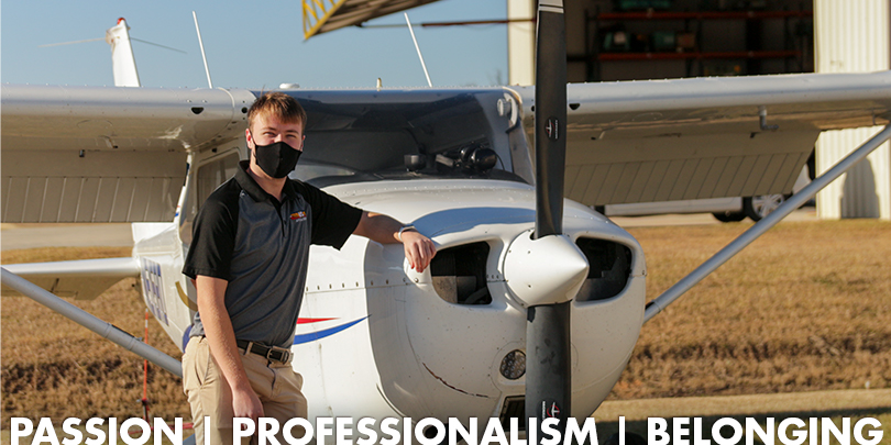 Man leaning against an airplane with the words Passion | Professionalism | Belonging written underneath.