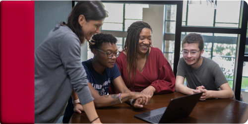 Students Smiling together looking at a computer 