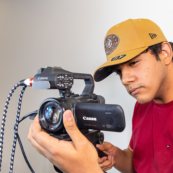 Photo of student filming video on a tripod