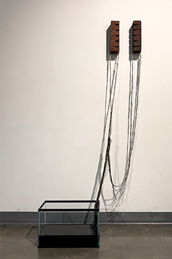 abstract sculpture made of Bricks, Candle wax, wicks, fish tank, water, and black ink sculpted by Katie Hagar