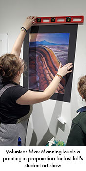 Volunteer Max Manning levels a painting in preparation for last fall's student art show. 