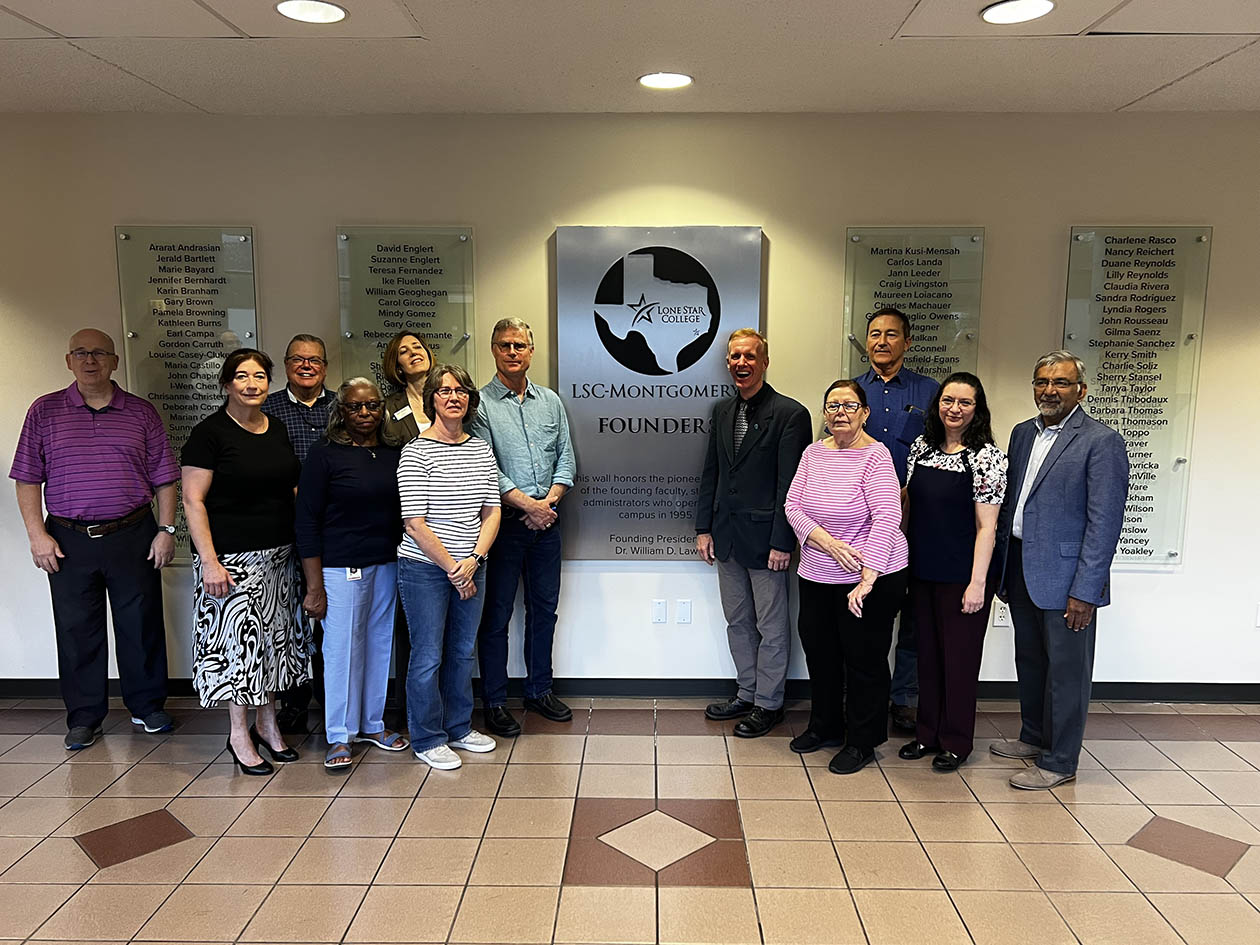 LSC-M founding employees standing in group by wall mounument