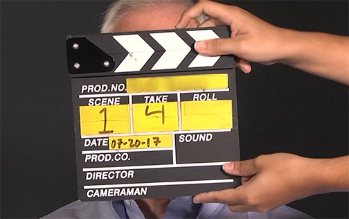 Photo of a movie clapper held in front of a person's face