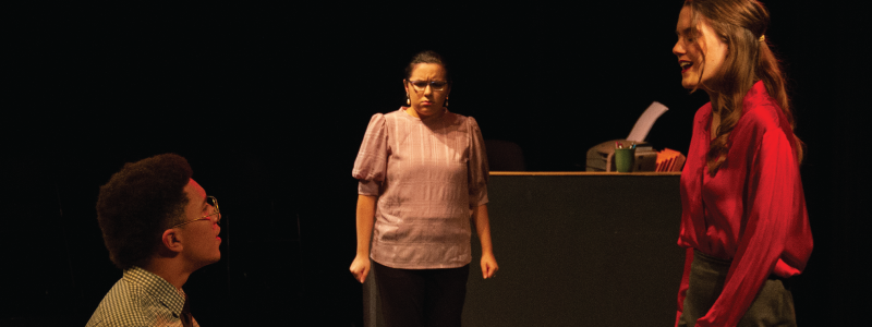 Man and woman having a conversation. There is a disgruntled woman in the background.