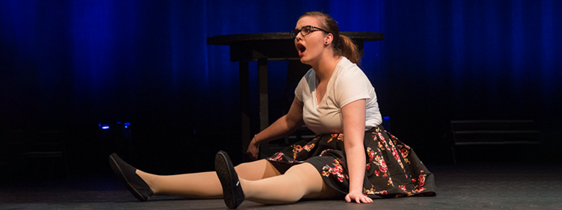 A woman sitting on the floor with an astonished look on her face.