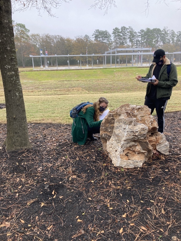 Physical Geology students observing a boulder on campus