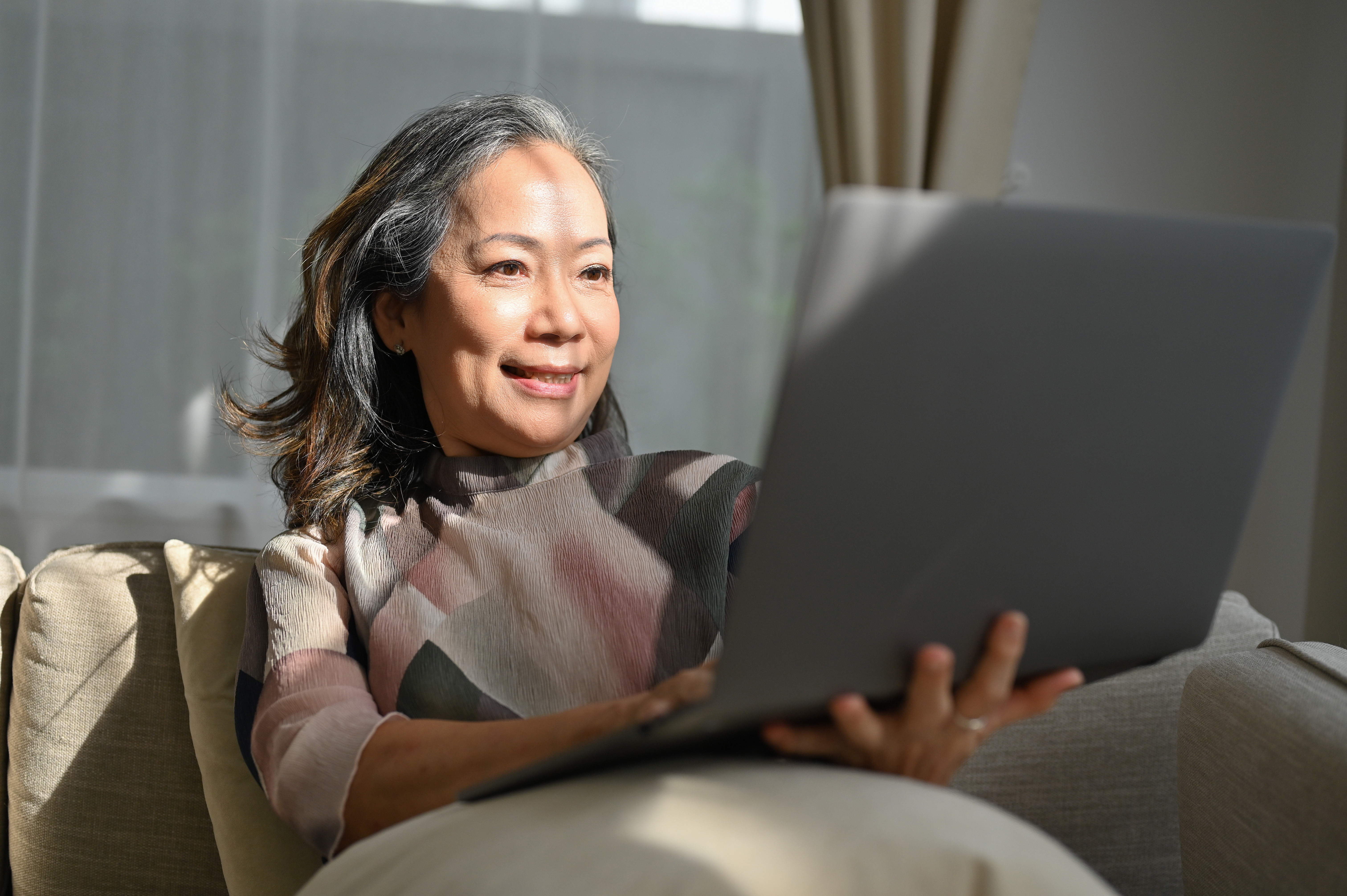 woman sitting on couch and looking at her laptop