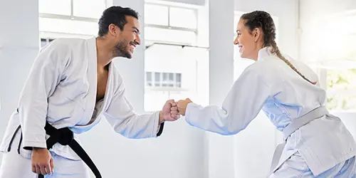 A man and a woman in gi fistbumping