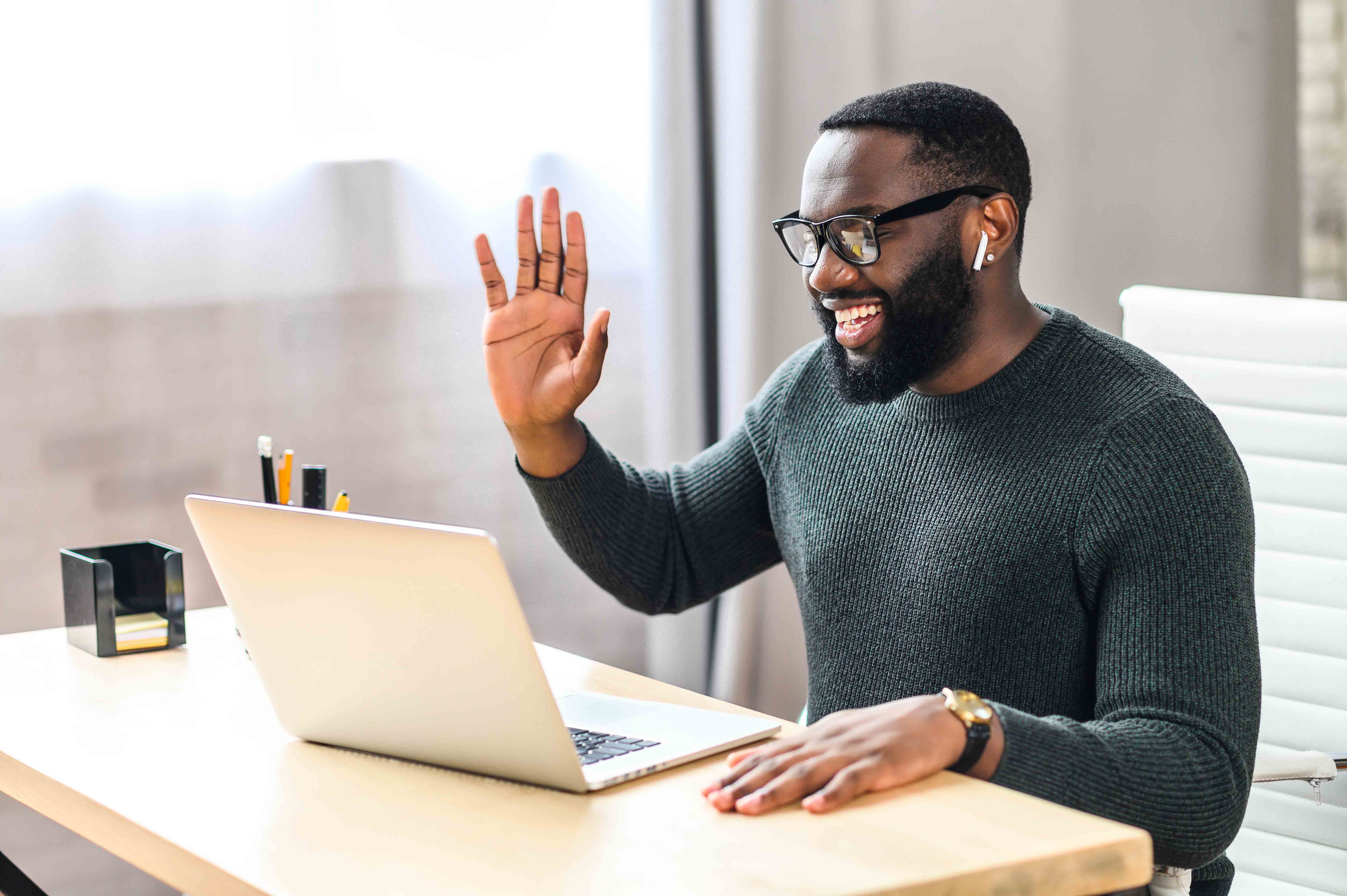 Man wearing headphones and waving to the computer