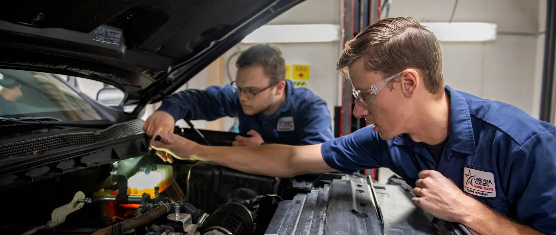 Lone Star College Students in the automotive program checking under the hood of a vehicle