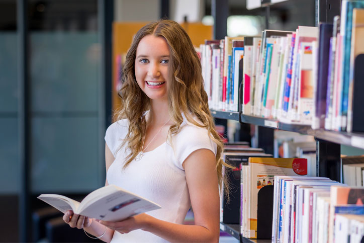 girl standing in the library with book