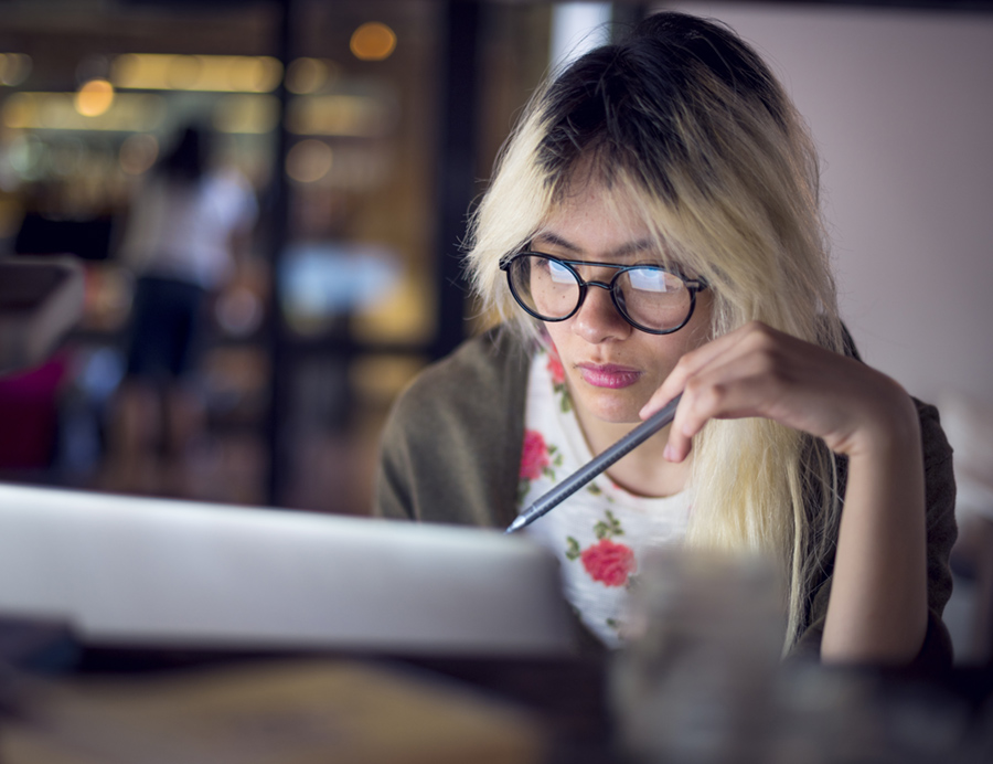 girl with glasses looking at a laptop screen