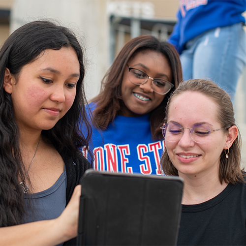 students looking at a tablet smiling