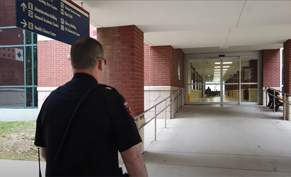 Lone star college police officer walking to college entry door