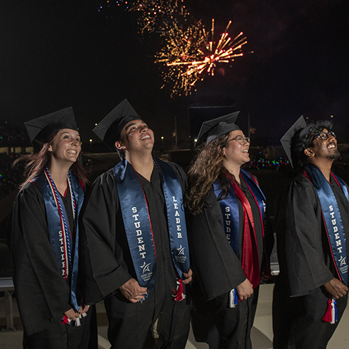 graduates with fireworks in background