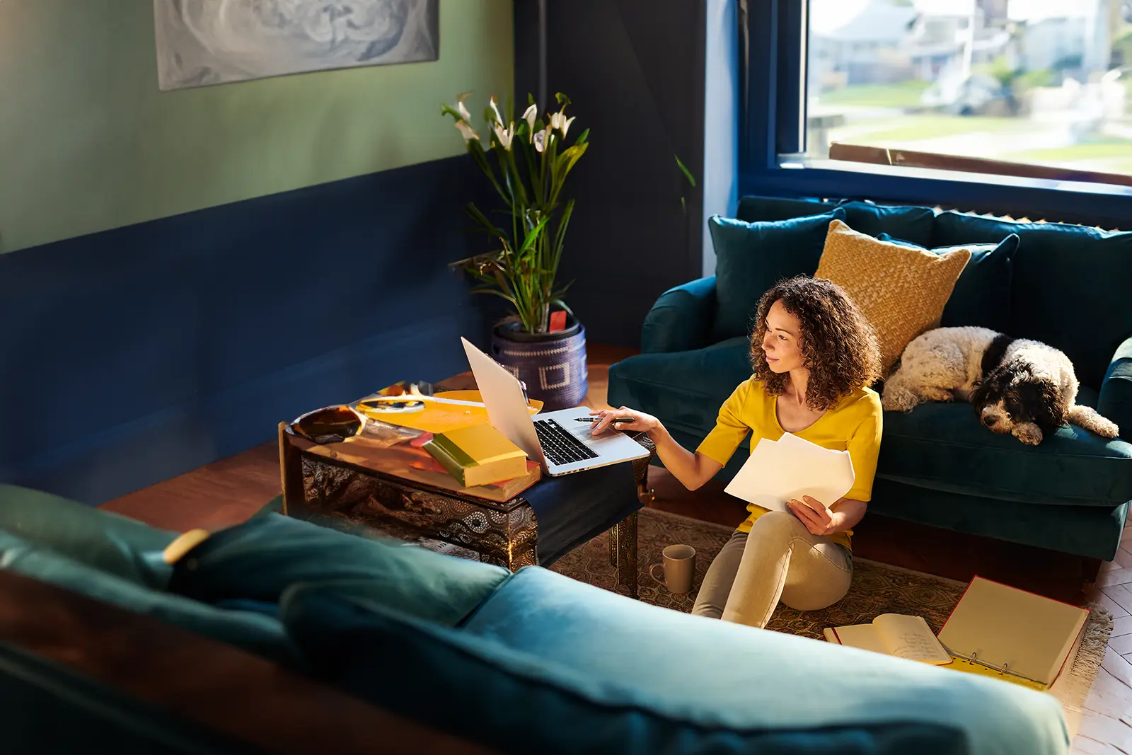 Student comfy at home with her laptop and dog