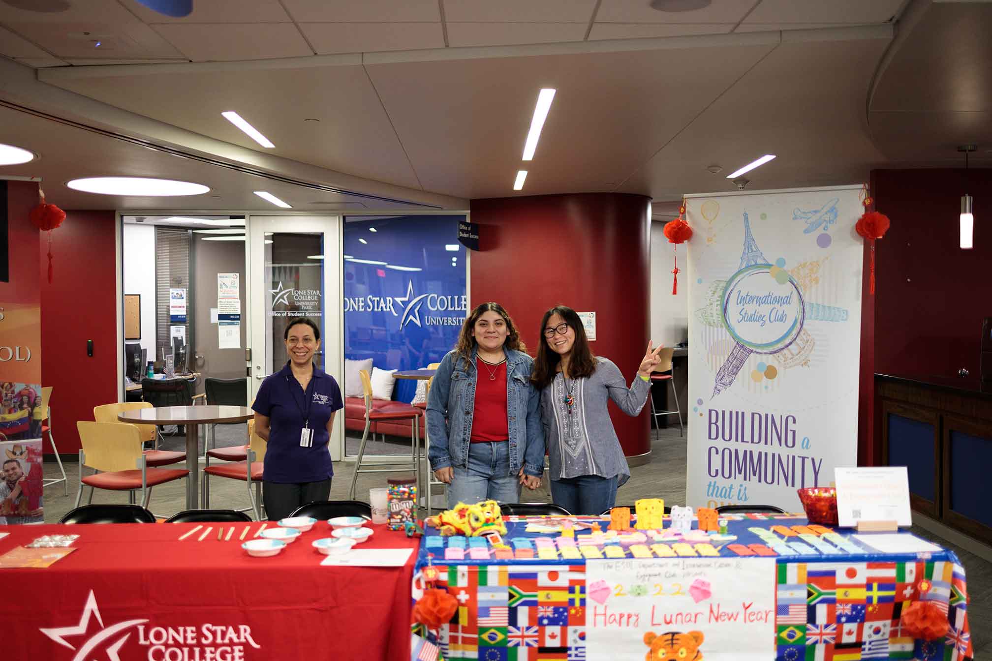 Three Women behind booth for Building Community and Happy Lunar New Year