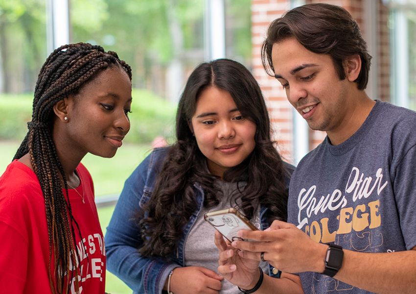 2 female students and male student looking at phone