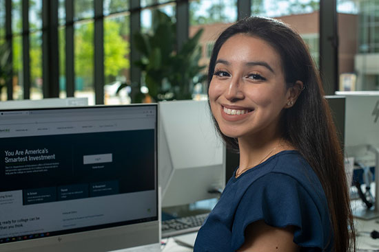 female student at computer looking at camera smiling