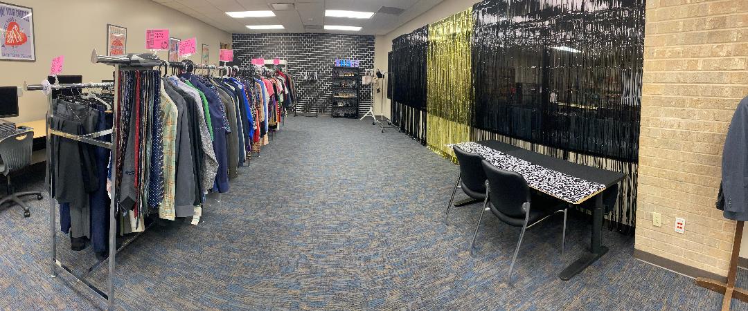 Photo of the Career Closet. There are several racks of professional clothing lined up with plenty of room to browse and several computers along the left-hand wall.