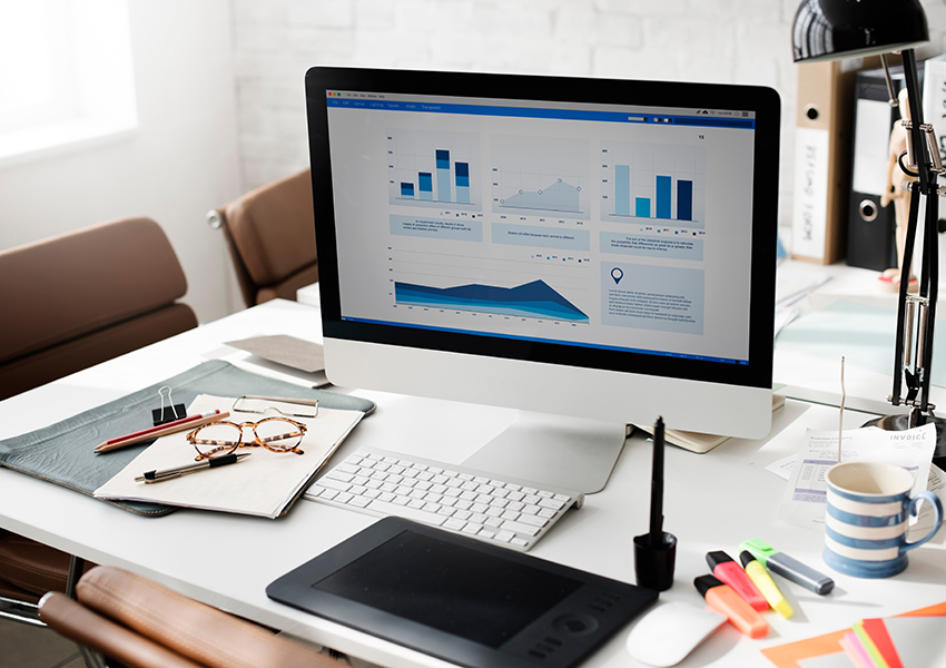 Overhead View of Desk with Analytics Reports on Computer Screen