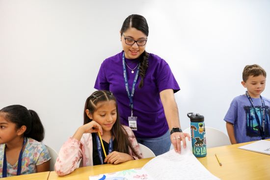 Smiling Teacher with Students reading in classroom