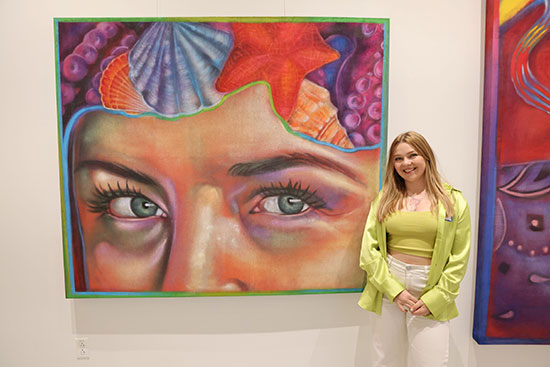 Lone Star College-University Park alum Taylor Barnes stands beside one of her large art murals from the “Taylord: Anemoia” exhibit.