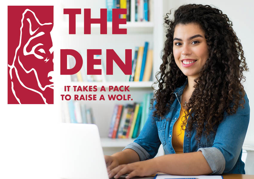 A red logo displaying half of a wolf's face in an outline-type design overlays the photo with text that reads: "The Den: It Takes a Pack to Raise a Wolf" - Photo of a smiling student in a casual denim long-sleeved top sitting at a table and working on a laptop in the foreground on the right side. Colorful books appear on shelves in the background.