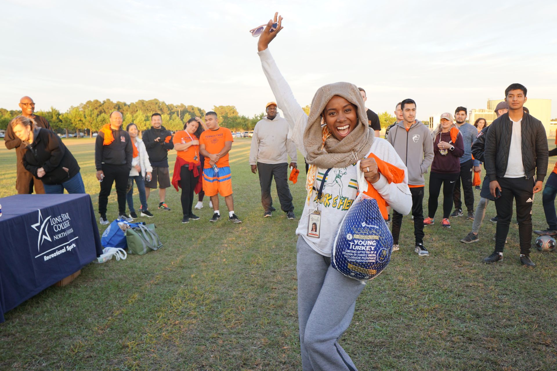 Photo of staff waving holding prize and students in background