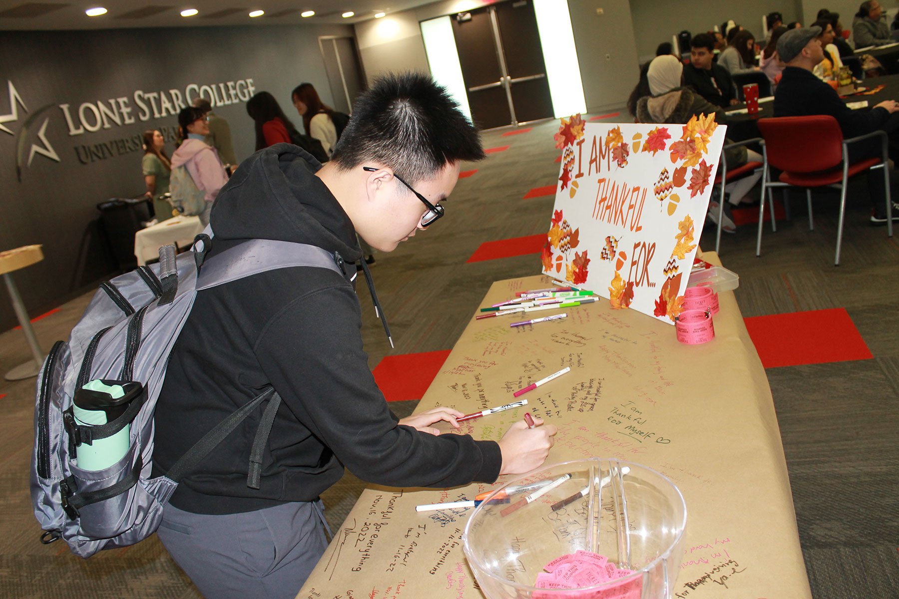 ESOL Student Writing on Collage of What They are Thankful For