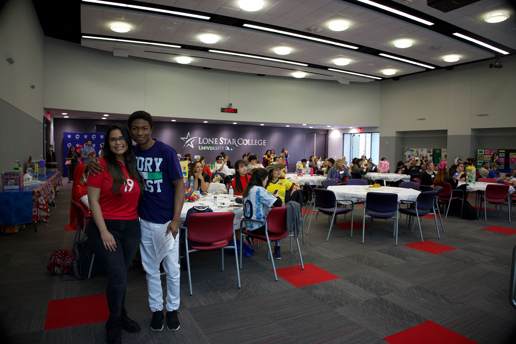 Two ESOL Students With Others in the Background Sitting at Tables